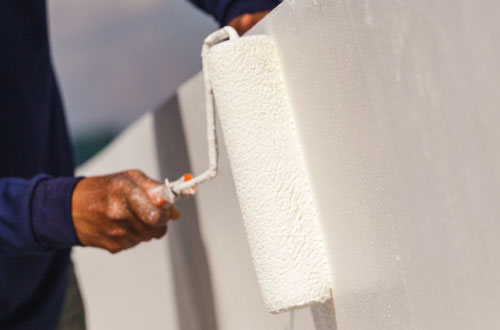 Rouleau de peinture sur mur blanc